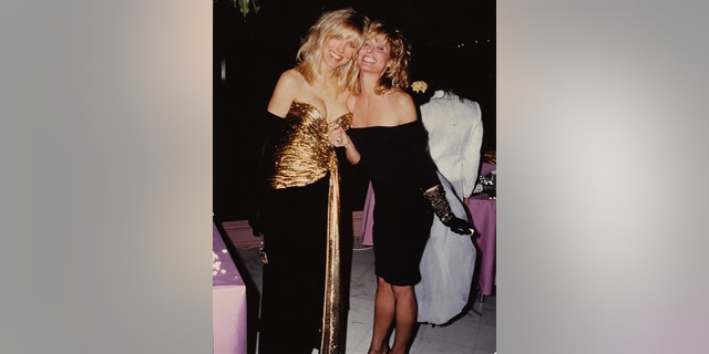 Alana Stewart wearing a black and gold dress next to Farrah Fawcett in a black cocktail dress