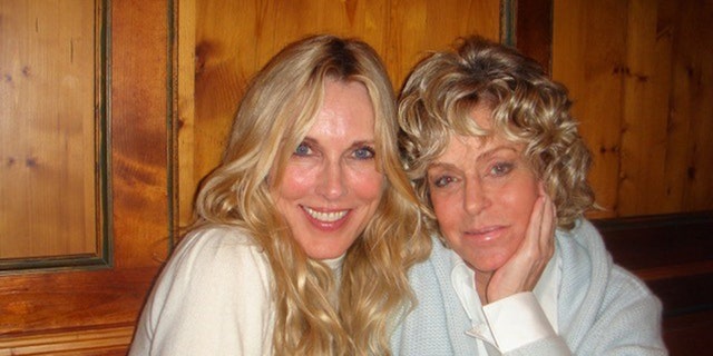 Farrah Fawcett wearing a sea green swear and a white shirt leaning next to Alana Stewart in a white sweater