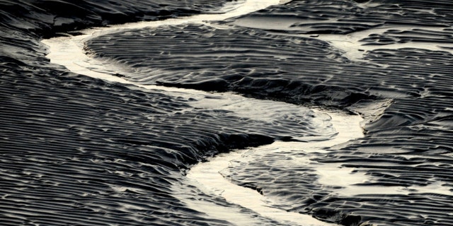 A channel flows through Alaska mud flats