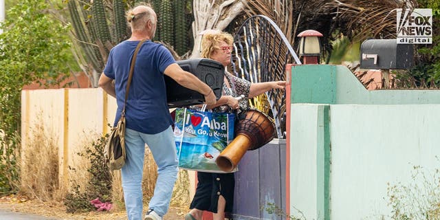 Joran van der Sloots mom, Anita carries a drum in her right hand, a water bottle under her arm, her male friend carries a big bluetooth speaker