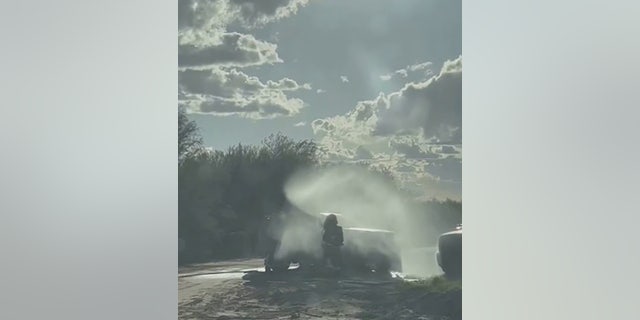 firefighter spraying foam around car
