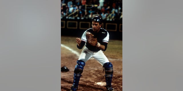 Kevin Costner stands behind home plate in Bull Durham