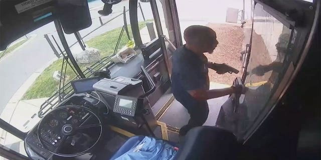 Bus driver standing at the front of the bus with his gun.