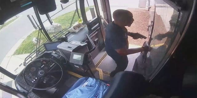 Bus driver standing at the front of the bus with his gun.