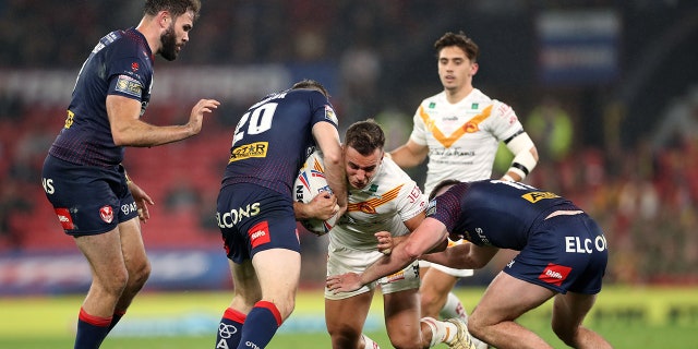 Catalans Dragons is tackled by a St Helens player