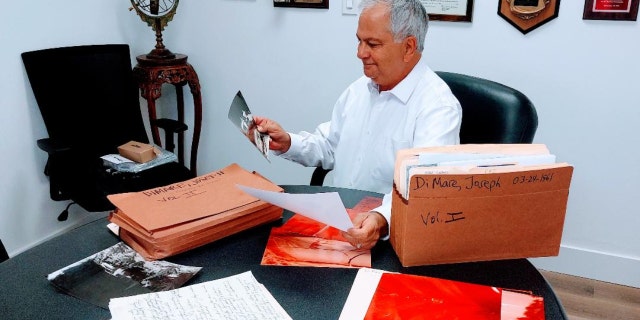 Attorney Paul Novack looks over photos in the Joseph DiMare murder case
