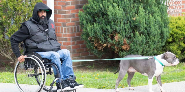 Edward Holley walks his dog outside his home in Middeltown