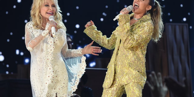 Dolly Parton in white suite performs with Miley Cyrus in gold suit