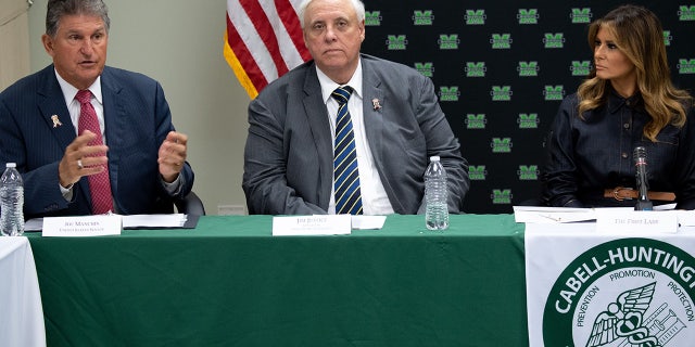 Jim Justice seen at a table between Melania Trump and Joe Manchin