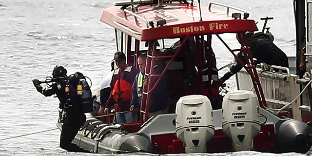 A Boston Fire diver jumps into the water off Castle Island