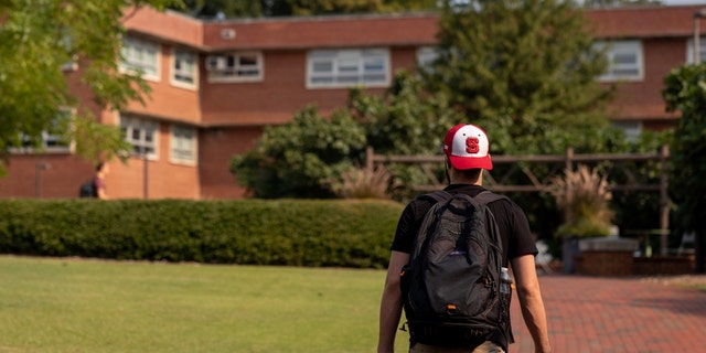 A student walks toward a dorm on the NCSU campus