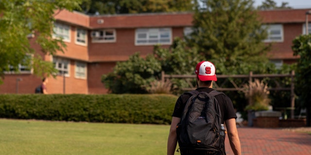 A student walks toward a dorm on the NCSU campus