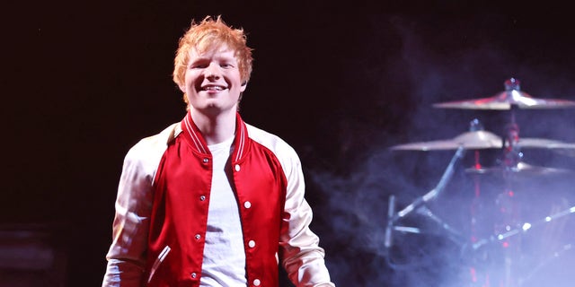 Ed Sheeran onstage in a red and white jacket.