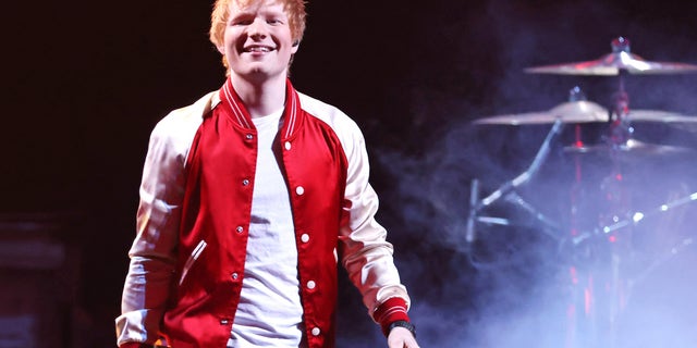 Ed Sheeran onstage in a red and white jacket.