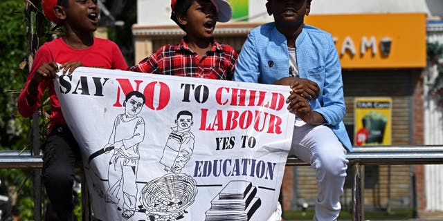 boys hold poster at demonstration against child labor