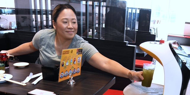 A robot waiter serves a woman at a restaurant in Orlando, Florida, in Sept. 2022. 