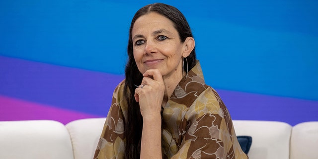 Justine Bateman puts her hand to her chin and soft smiles on the couch at the TODAY show