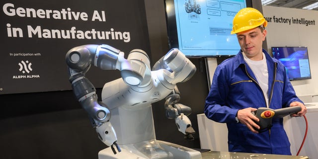 Seorang pria mendemonstrasikan robot yang dikendalikan AI di Hanover, Jerman, pada 16 April 2023.