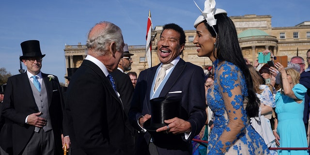 King Charles with his back to the camera shares a laugh with Lionel Richie and his girlfriend Lisa Parigi at the Garden Party at Buckingham Palace ahead of the coronation