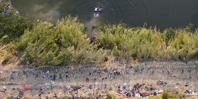 Migrants enter a clothing-cluttered area near the U.S.-Mexico border