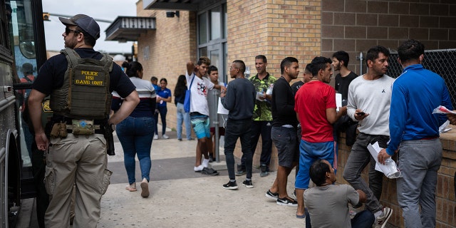 Migrants in a line near a bus in Texas