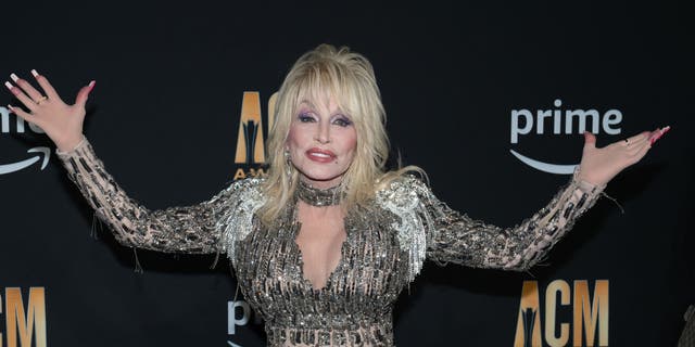 Dolly Parton puts her arms out at the ACM Awards carpet in a sparkly, sequined outfit
