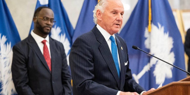 Gov. Henry McMaster speaks to reporters with South Carolina Comptroller General Brian Gaines standing behind him