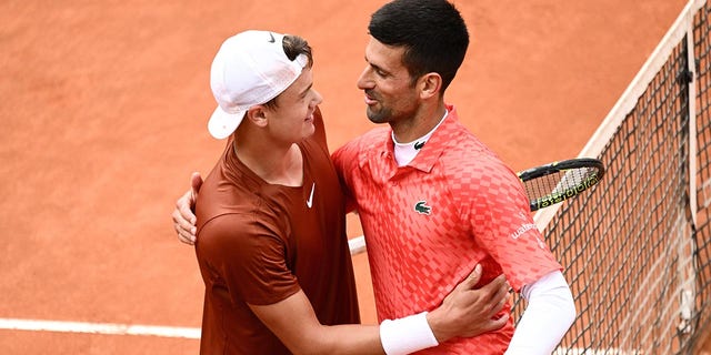 Holger Rune and Novak Djokovic shake hands on center court after their quarterfinal match