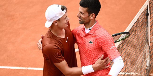 Holger Rune and Novak Djokovic shake hands ay center court after their quarterfinal match