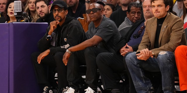 Dave Chappelle wears sunglasses next to Jack Nicholson and his son Ray Nicholson at Lakers game