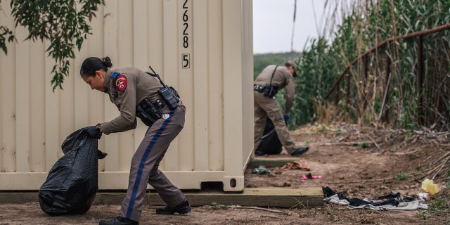 DEL RIO, TEXAS - MAY 17: Texas Highway Patrol officers clean up trash at a crossing site near the Rio Grande river on May 17, 2021 in Del Rio, Texas. A surge of mostly Central American immigrants crossing into the United States has challenged U.S. immigration agencies along the U.S. Southern border. (Photo by Brandon Bell/Getty Images)