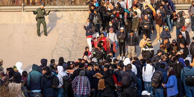 Border Patrol agent and migrants at the border