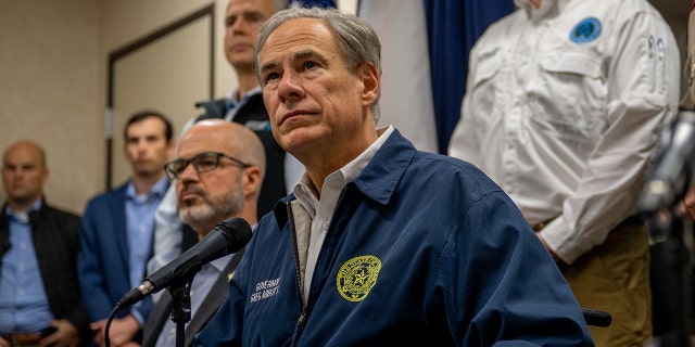 Greg Abbott sitting at a table with a microphone