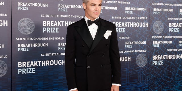 Chris Pine in a tuxedo on a red carpet.