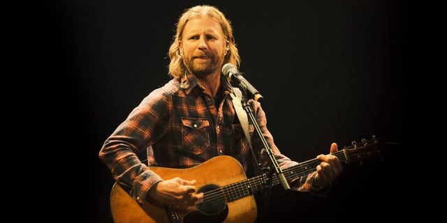 Dierks Bentley onstage in a plaid shirt with a guitar.
