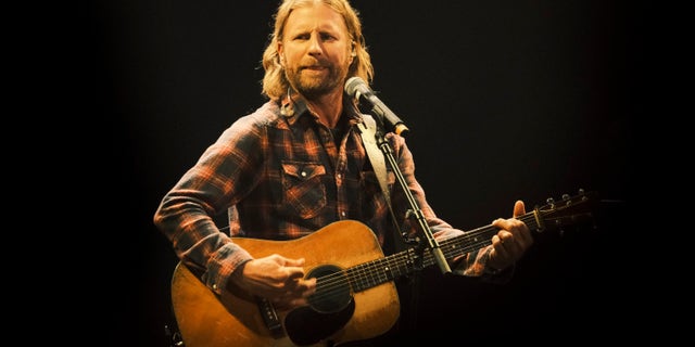 Dierks Bentley onstage in a plaid shirt with a guitar.