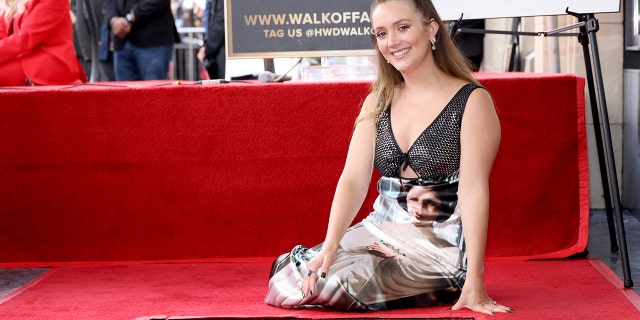 Billie Lourd sits on the red carpet and smiles with her late mother Carrie Fisher's new star on the Walk of Fame