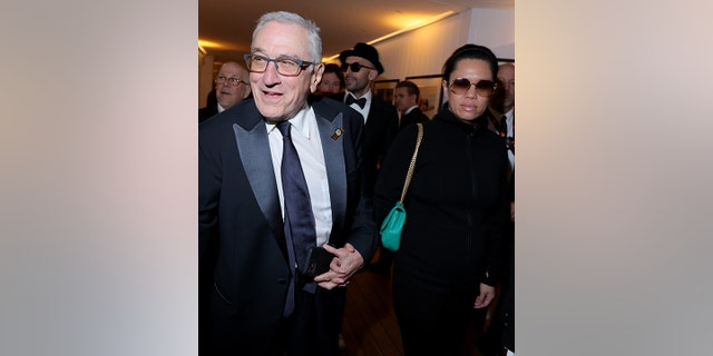 Robert De Niro smiles as he holds Tiffany Chen's hand and walks into the Vanity Fair x Prada party