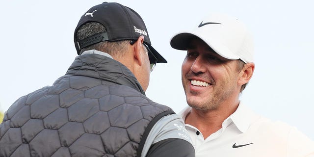 Brooks Koepka and trainer Claude Harmon III embrace after winning the 2023 PGA Championship