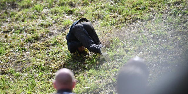 A woman falls down the hill at the annual cheese rolling race in England