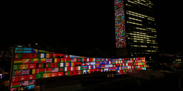 National flag projections are seen over the UN general assembly building headquarters.