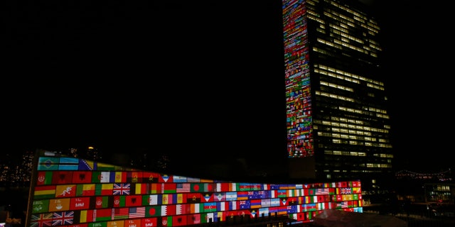 National flag projections are seen over the UN general assembly building headquarters.