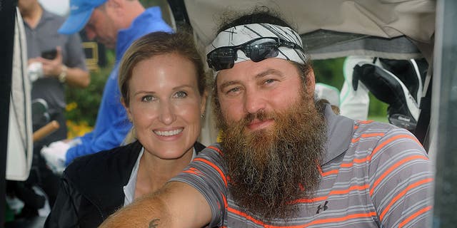 willie and korie robertson smiling in golf cart