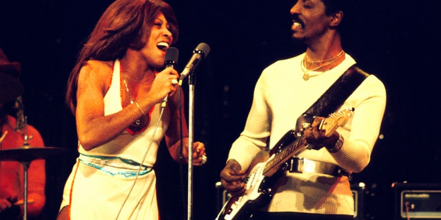 Tina Turner performs in a white dress alongside Ike Turner.