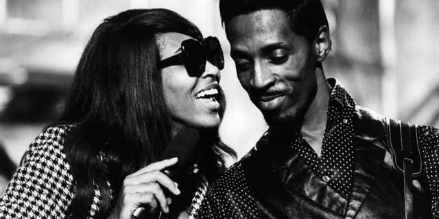 Tina Turner performs wearing sunglasses with Ike Turner in black and white photo.