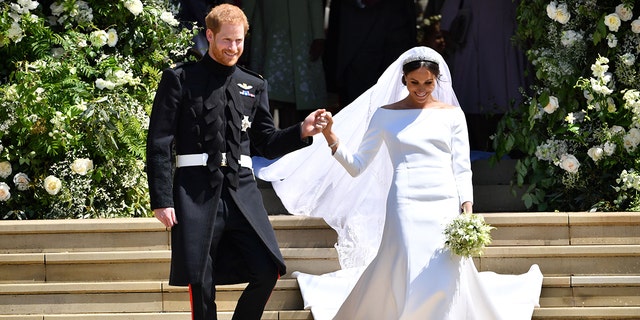 Prince Harry holds Meghan Markles hand as they walk down the stairs at Georges Chapel where they just got married at Windsor Castle