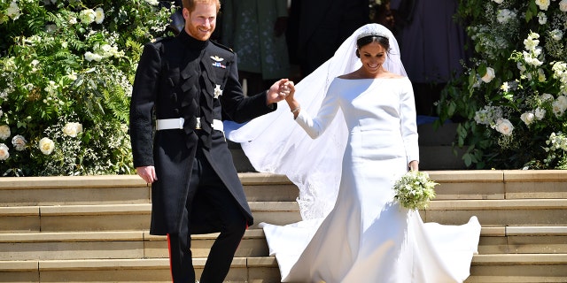 Prince Harry holds Meghan Markle's hand as they walk down the stairs at George's Chapel where they just got married at Windsor Castle