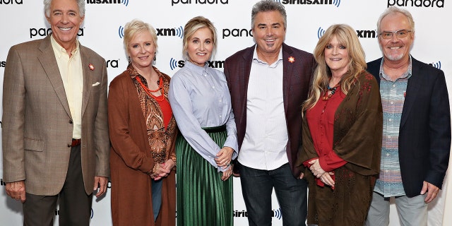 The Brady kids today posing in front of a white step and repeat