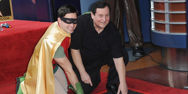 Burt Ward with a Robin impersonator bending down to touch a star on the Hollywood walk of fame