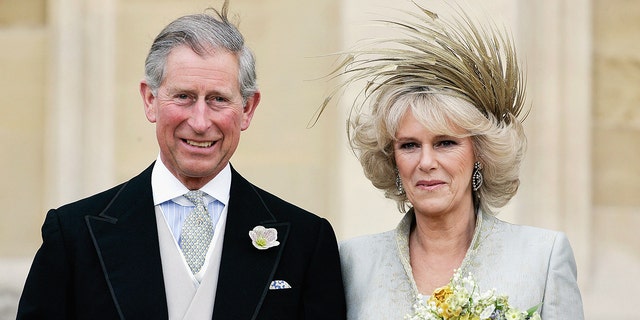 Prince Charles in a suit next to his bride Camilla wearing a bridal gown